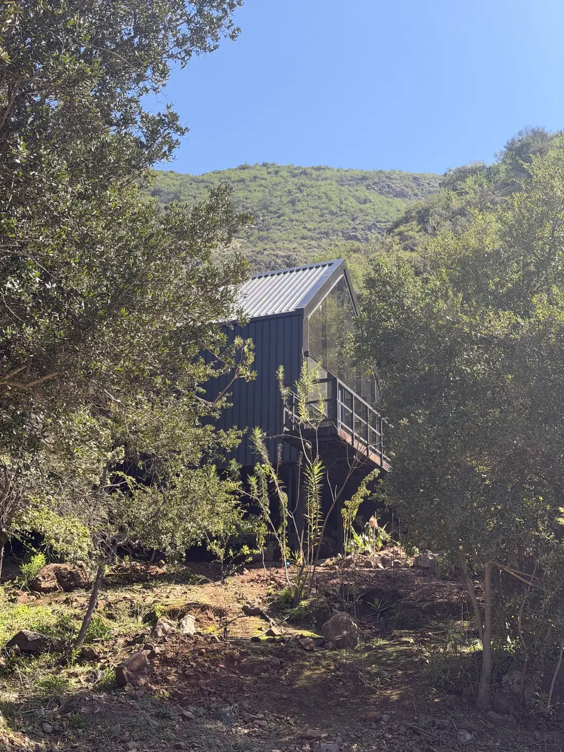 Casa de fachada oscura integrada al bosque nativo